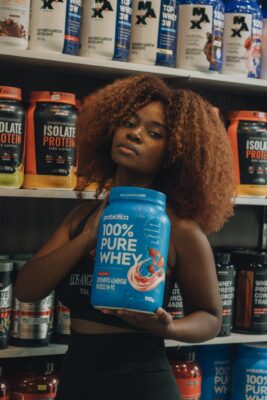 young woman holding protein supplement in store